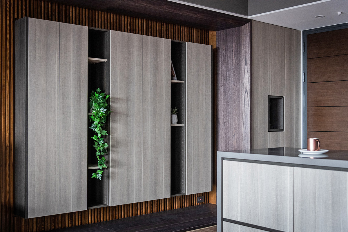 Thiết kế lối vào căn hộ gây ấn tượng với hệ tủ lưu trữ bằng gỗ ốp tường màu xám, xen kẽ kệ mở để trưng bày những chậu cây trang trí đẹp mắt.