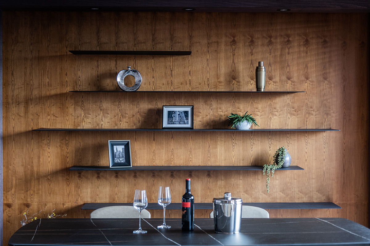 Bức tường gỗ tại phòng ăn được thiết lập những chiếc kệ mở bằng tấm kim loại mỏng, là nơi để anh chàng trưng bày một vào món đồ trang trí mình yêu thích.