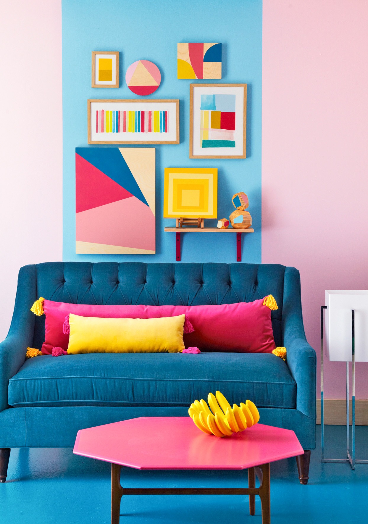 Bạn hãy kết hợp cả màu sơn tường nổi bật như hồng, xanh lam,... với các tác phẩm nghệ thuật chủ đề hình học, song song với đó là nội thất bắt mắt như sofa, bàn nước trong hình, chắc chắn sẽ làm cho phòng khách siêu nổi bật.