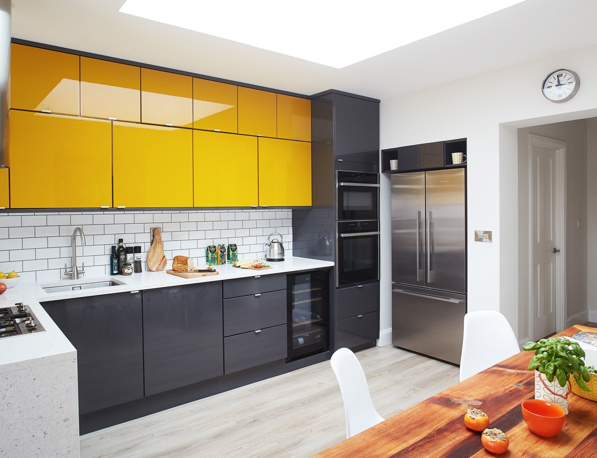 Không gian phòng bếp rộng rãi với giếng trời thoáng sáng, phản chiếu ánh sáng lên bề mặt hệ thống tủ lưu trữ trên và dưới với tone màu vàng mù tạt - đen xám bóng bẩy. 