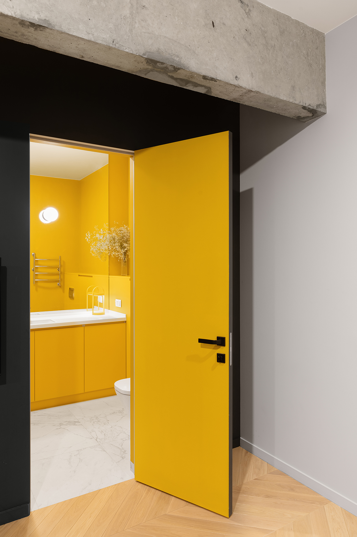 Thật bất ngờ khi đằng sau bức tường toàn màu đen là cánh cửa dẫn lối vào phòng tắm rực sáng với sắc vàng chiếm lĩnh từ mặt trong cánh cửa, tường cho đến tủ vanity.