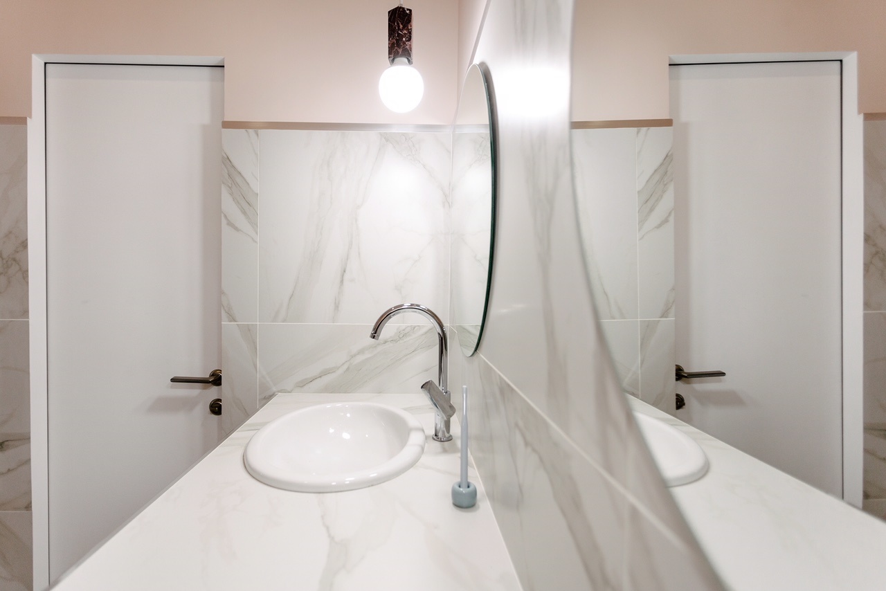 Bên cạnh tấm gương gương khổ dọc đặt trên sàn ở lối ra vào thì cặp gương hình tròn trong phòng tắm phản chiếu ánh sáng từ đèn thả trần cũng giúp “cơi nới” không gian bằng thị giác.