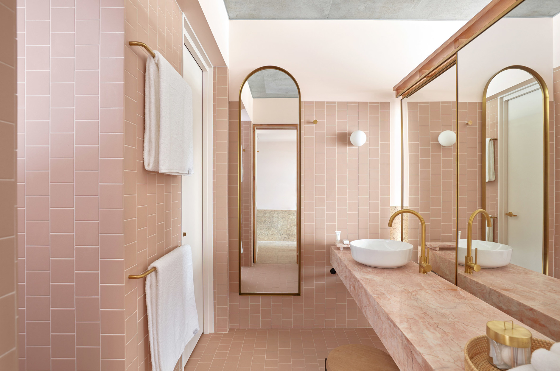 Phòng tắm thu hút bởi vẻ đẹp của những viên gạch hồng vuông vức ốp lát tường và sàn nhà, thêm vào mặt bàn bồn rửa bằng đá với màu sắc 'tone sur tone' ấn tượng.