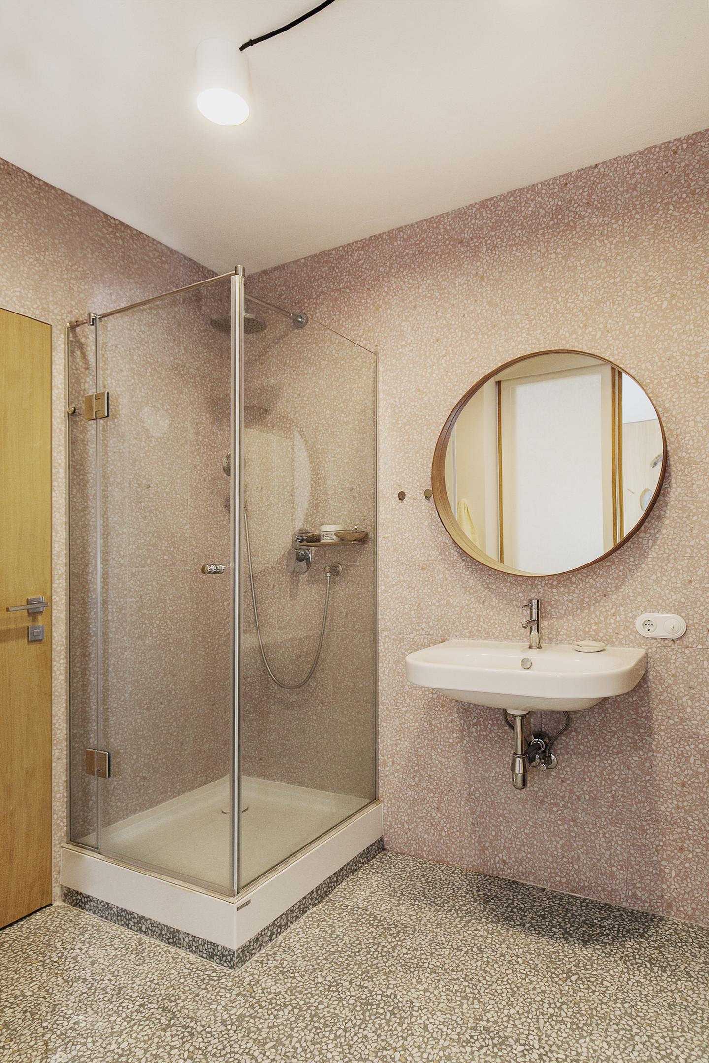 Phòng tắm tối giản nhưng quyến rũ nhờ sự kết hợp của gạch ốp tường hồng nữ tính và gạch lát sàn xám thanh lịch tạo sự tương phản nhẹ nhàng với trần nhà trắng sáng.