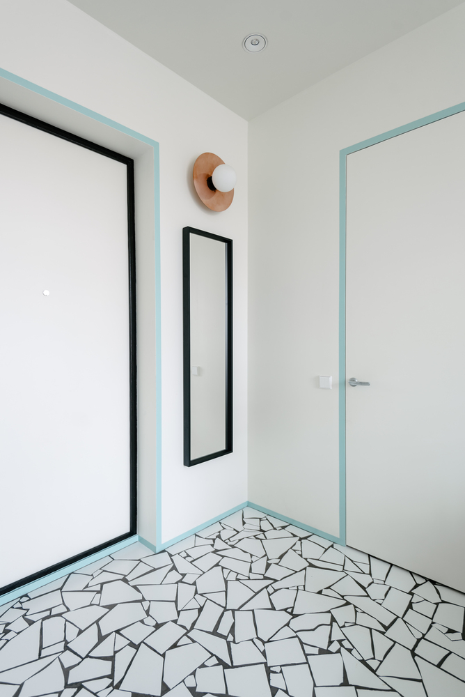 Lối vào căn hộ cực kỳ đơn giản, chỉ với tấm gương khổ dọc, đèn gắn tường cùng 'đường viền' màu xanh lam trên phông nền trắng chủ đạo.