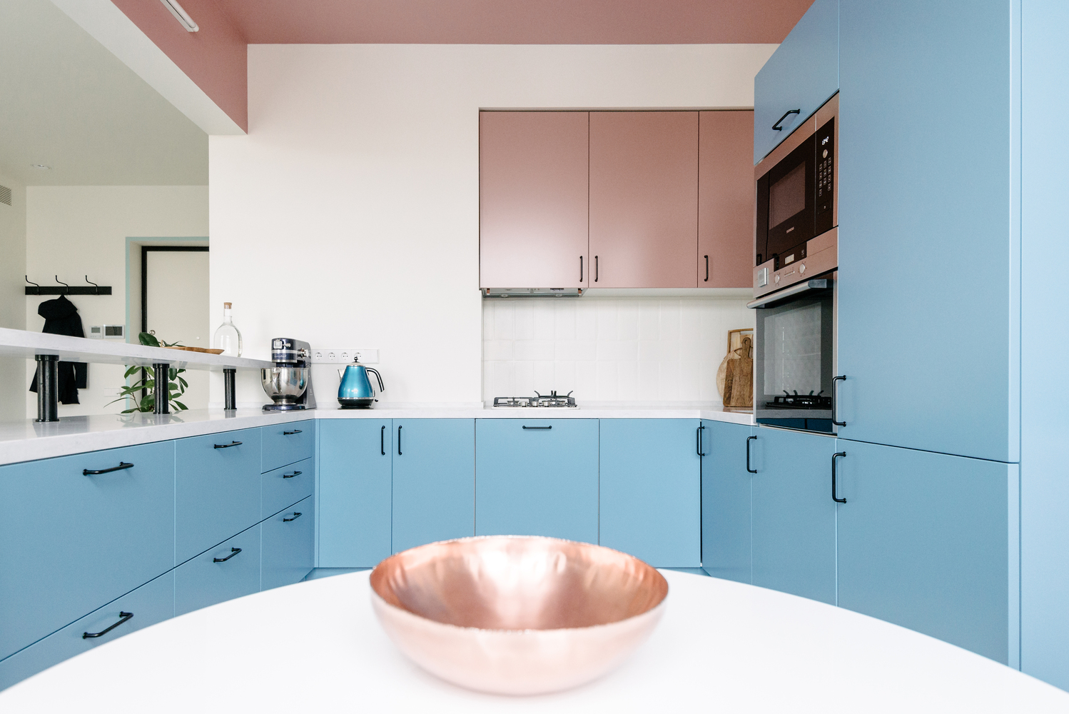 Phòng bếp thiết kế kiểu chữ U với nội thất xếp gọn gàng trong các hộc tủ. Nếu màu xanh lam mang đến sự nhẹ nhàng, mát mẻ cho phòng bếp vốn dễ gây cảm giác nóng nực thì sắc hồng lại tô điểm cho 'trái tim ngôi nhà' nổi bật hơn.