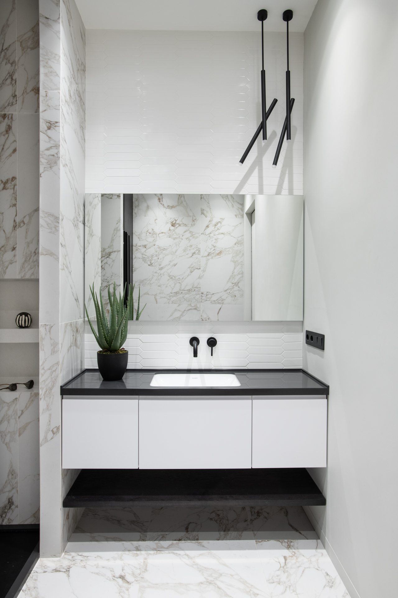 Phòng tắm và nhà vệ sinh sáng sủa với sơn tường màu trắng cùng đá cẩm thạch ốp lát sang chảnh. Một chậu cây nha đam đặt trên bồn rửa vừa có tác dụng thanh lọc không khí vừa mang thiên nhiên vào không gian sống.