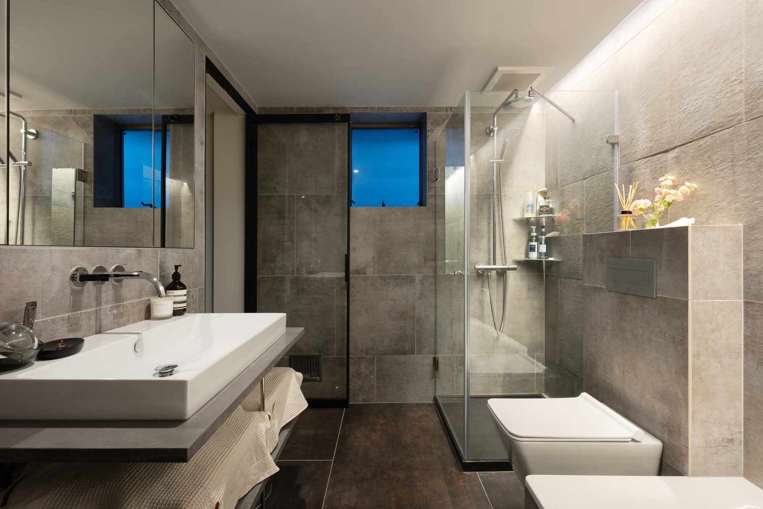 Phòng tắm và nhà vệ sinh được bố trí ở tầng 2 với gạch ốp lát màu xám sang trọng. Khu vực buồng tắm phân vùng với toilet bằng cửa kính trong suốt đẹp mắt.