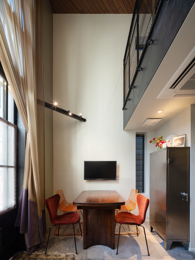 Khu vực phòng khách thiết kế đơn giản với chiếc bàn gỗ vững chãi, những chiếc ghế màu cam nổi bật cho cảm giác ấm cúng.