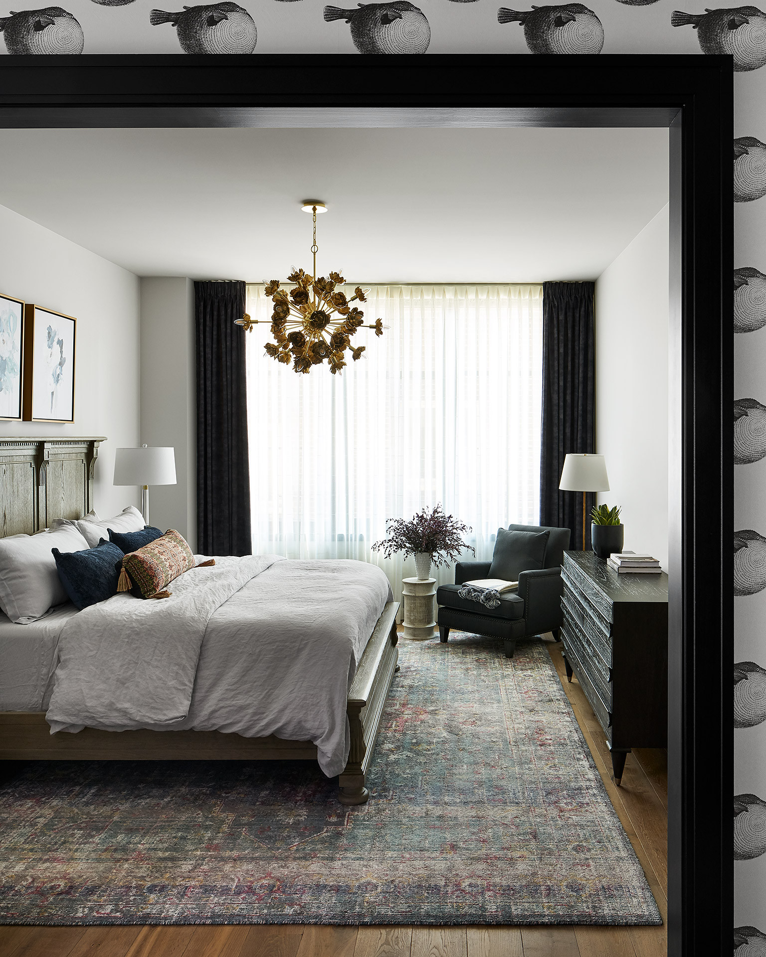 Phòng ngủ thiết kế theo phong cách chiết trung phóng khoáng, bổ sung thảm trải sàn, đèn thả trần và gối tựa nhiều màu sắc trầm ấm bổ sung cho 2 gam màu trắng đen chủ đạo.