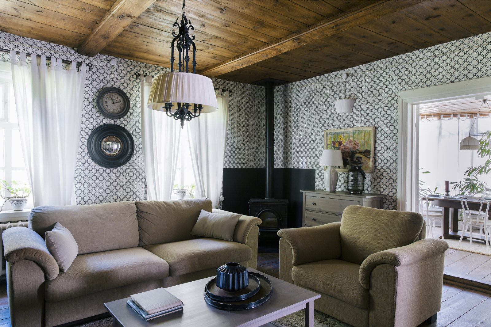 Phần trần dầm gỗ được giữ nguyên hiện trạng và chỉ vệ sinh sạch sẽ. Bộ sofa và ghế bành tone màu trầm ấm, kết hợp chiếc bàn nước gỗ tối giản cho cảm giác gần gũi hơn.