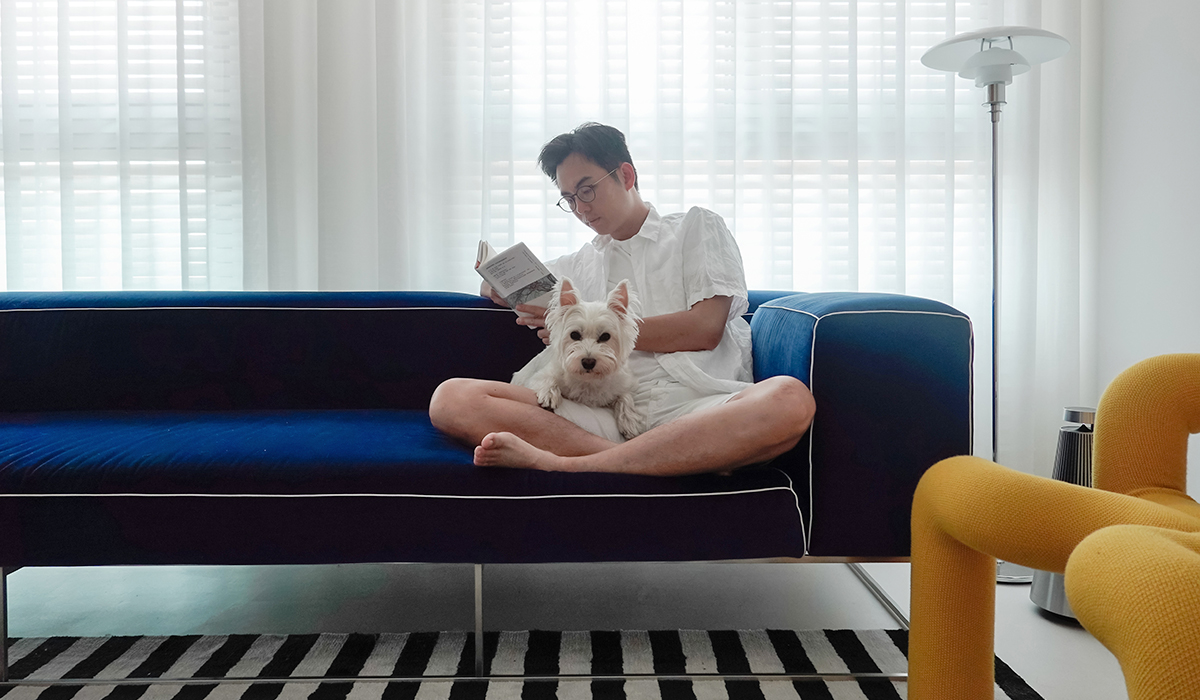 Người chồng cùng chú chó cưng trên ghế sofa phòng khách, thư giãn bằng cách chiêm nghiệm một sách hay.