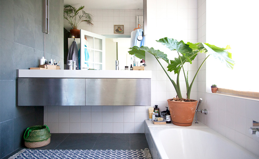 Phòng tắm thiết kế bồn tắm nằm thoải mái bên cạnh ô cửa sổ thoáng sáng và chậu cây sinh động. Chiếc tủ vanity gắn tường với bề mặt thép không gỉ sáng bóng, giải phóng diện tích sàn hiệu quả.