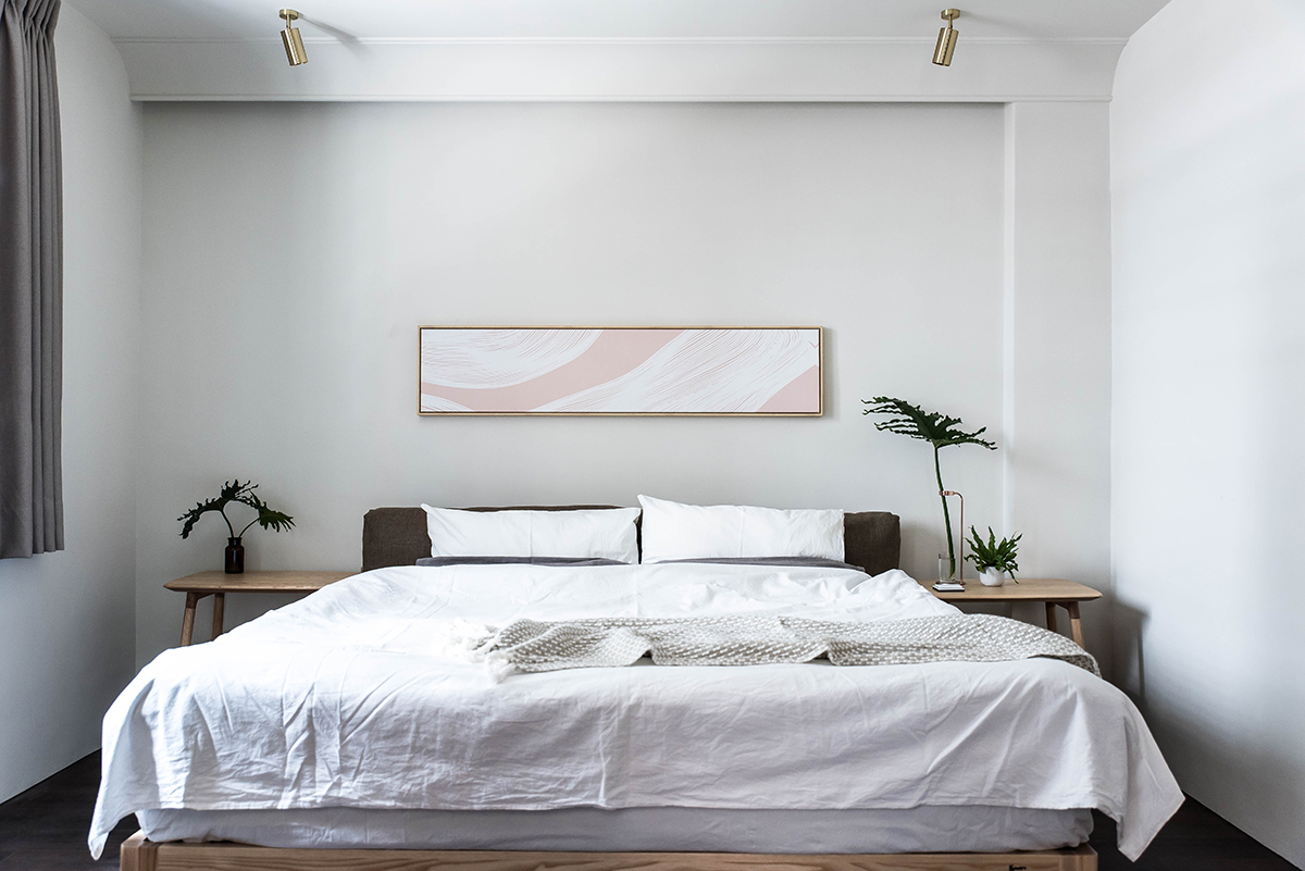 Phòng ngủ đầu tiên sử dụng tone màu trắng chủ đạo, nội thất trang trí cân xứng với hai chiếc táp đầu giường nhỏ gọn, đèn rọi ray bằng kim loại mạ vàng đồng phía trên trần nhà tuy đơn giản nhưng đẹp mắt.