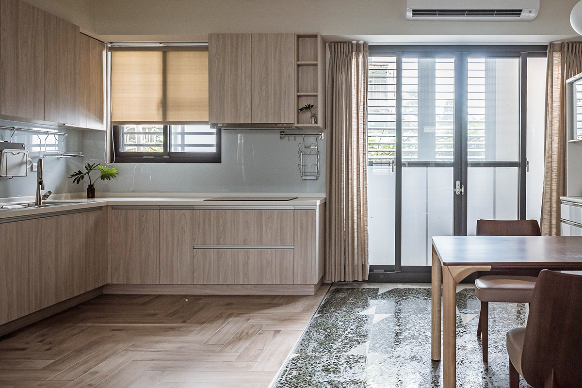 Riêng khu vực phòng bếp được lát sàn gỗ, tương đồng với hệ thống tủ lưu trữ trên và dưới cho cái nhìn gần gũi, ấm áp. Thiết kế bếp kiểu chữ L cũng phù hợp với cấu trúc ngôi nhà cũng như tiết kiệm diện tích.