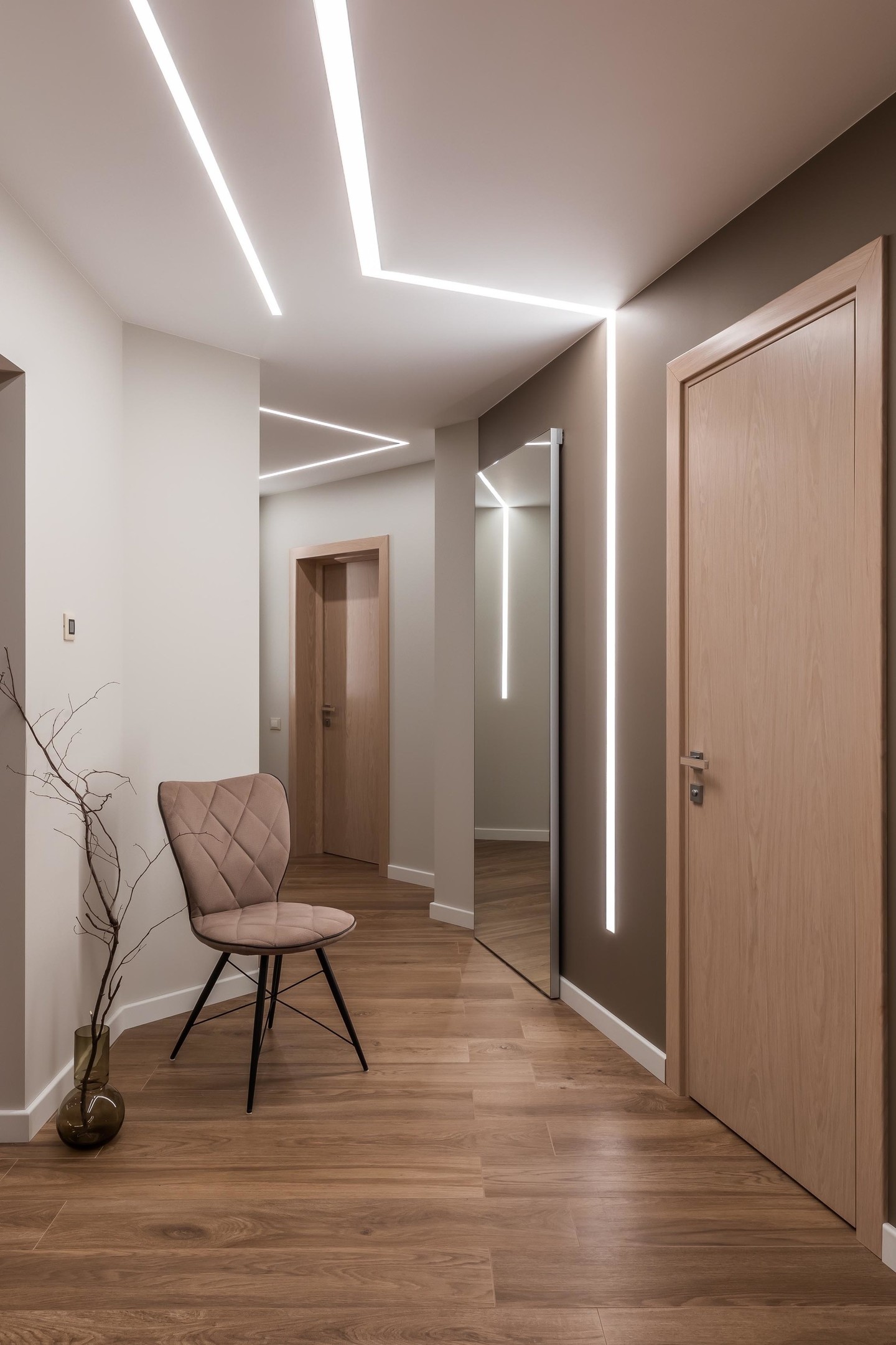 Lối vào căn hộ siêu đẹp với hệ thống đèn Led tuyến tính tích hợp, kéo dài từ trần nhà đến bức tường, phản chiếu qua cửa trượt gương càng 'nhân đôi' ánh sáng.