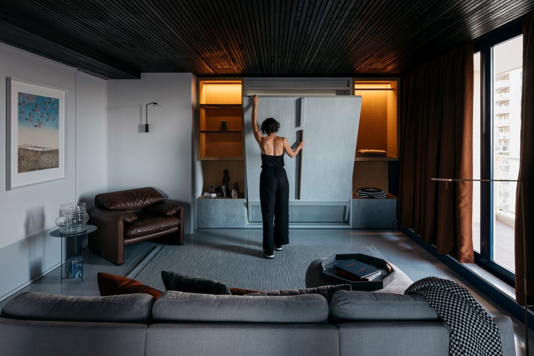 Trần ốp gỗ tối màu tạo cảm giác gần gũi và ấm áp cho không gian phòng khách vốn rộng lớn, sử dụng tone màu chủ đạo cùng nội thất sang trọng.
