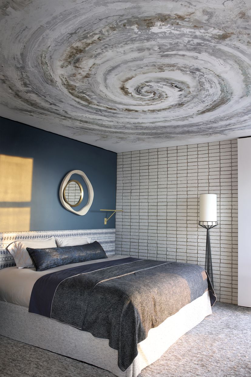Phòng ngủ cho cảm giác siêu thực với trần nhà được vẽ tay hình xoắn ốc như một cơn lốc xoáy, đồng thời khiến trần nhà cho vẻ cao hơn so với thực tế. 