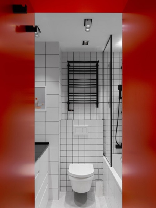 Nhà vệ sinh hiện đại với toilet gắn tường đặt tại vị trí trung tâm, phân tách với bồn tắm nằm bằng vách ngăn cửa kính tương tự phòng ngủ. Rất nhiều hệ thống đèn trần, đèn gắn tường được lắp đặt để cung cấp ánh sáng cho không gian thiếu cửa sổ.