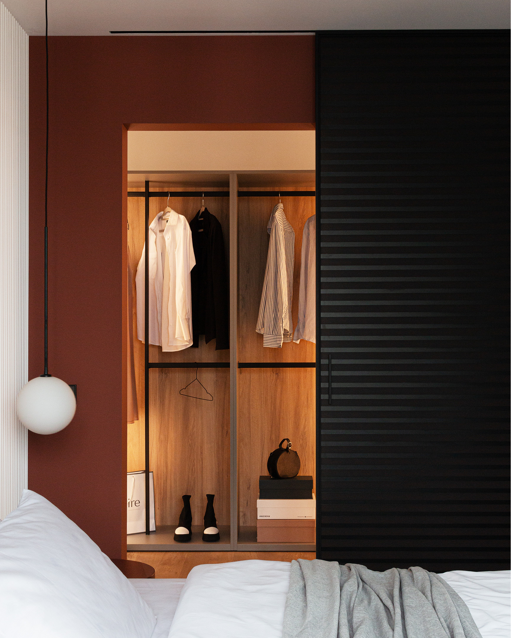Góc trái phòng ngủ là tủ quần áo thiết kế kiểu cửa trượt màu đen, bên trong sơn màu đất nung hòa cùng ánh đèn vàng và nội thất gỗ sang chảnh như trong khách sạn.