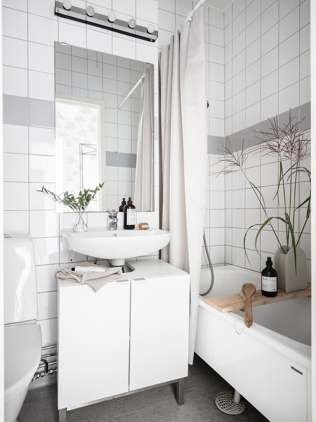 Tủ vanity kết hợp bồn rửa bố trí giữa toilet và bồn tắm nằm. Nội thất phòng tắm khá nhỏ gọn nhưng đầy đủ tiện nghi, đặc biệt là gương soi giúp phản chiếu ánh sáng.