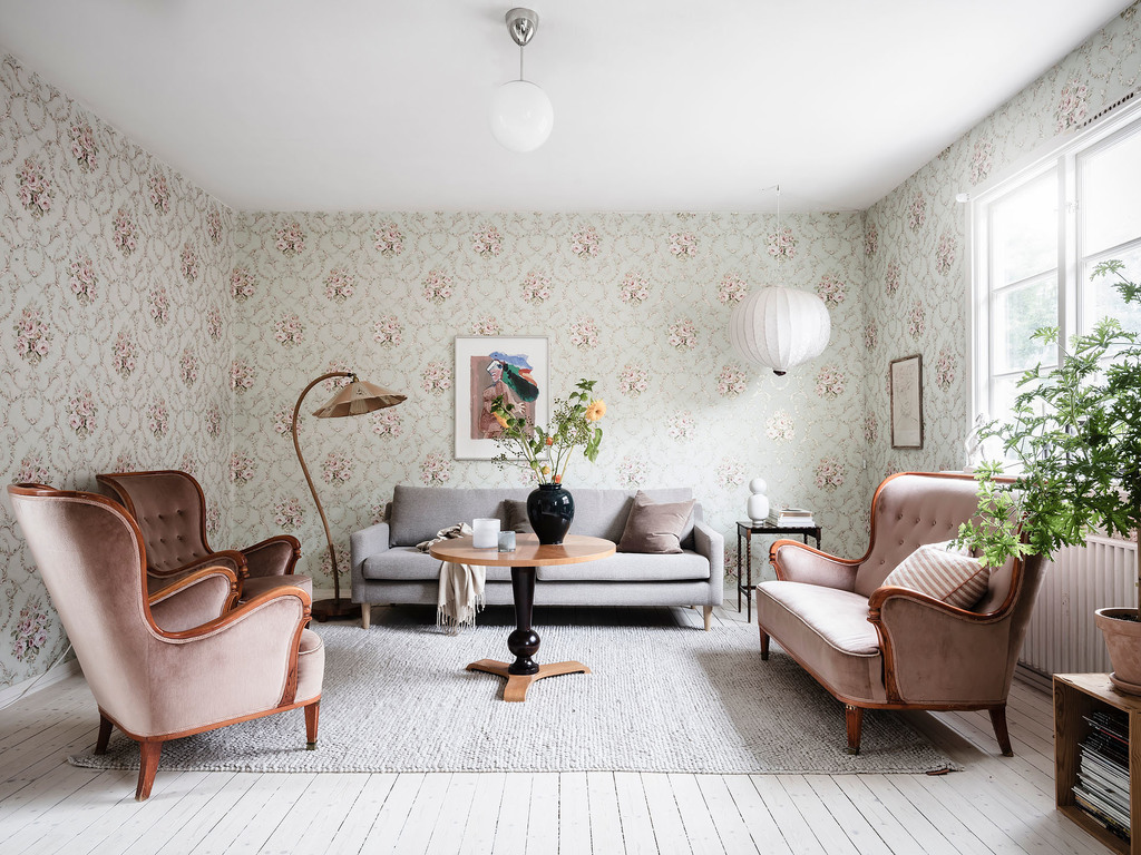 Toàn bộ phòng khách sử dụng giấy dán tường hoa văn kiểu vintage nhẹ nhàng, nội thất kết hợp giữa cổ điển và hiện đại, chẳng hạn như 2 mẫu ghế sofa tạo nên vẻ đẹp sang trọng.