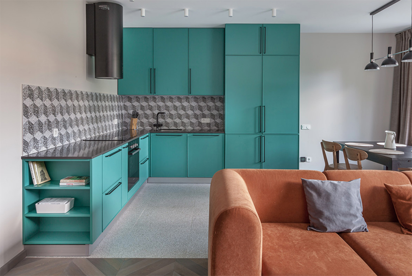Phòng bếp thiết kế kiểu chữ L tiện nghi và phù hợp với cấu trúc của căn hộ. Toàn bộ hệ thống tủ bếp sơn gam màu xanh ngọc lục bảo thời thượng, kết hợp gạch ốp backsplash trắng - xám sang trọng. 