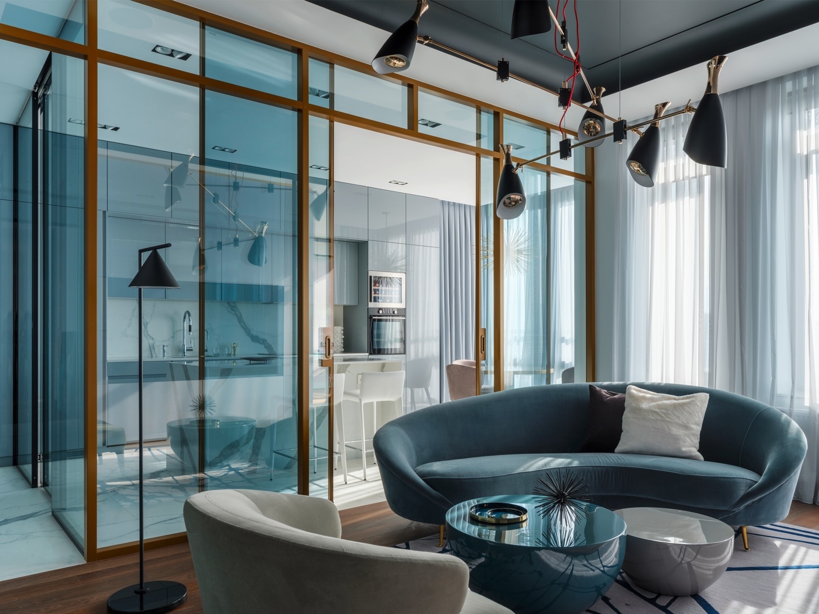 Căn phòng không sử dụng nhiều màu sắc nhưng vẫn quyến rũ nhờ sofa hình bán nguyệt màu xanh lam. Nó cũng là tiền đề để NTK nội thất bổ sung bàn nước và cửa kính trượt cùng tone màu để tạo nên sự hấp dẫn thị giác ấy.
