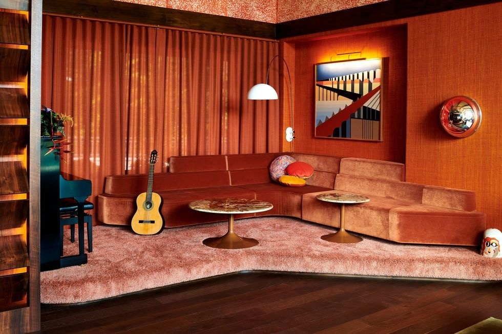 Nếu bạn là người cá tính, sẵn sàng chơi đùa cùng màu sắc thì có thể tham khảo ý tưởng 'hô biến' phòng khách thành một sân khấu với sofa cong màu cam gạch bọc vải nhung sang chảnh giữa phông nền cũng “rực lửa” không kém.