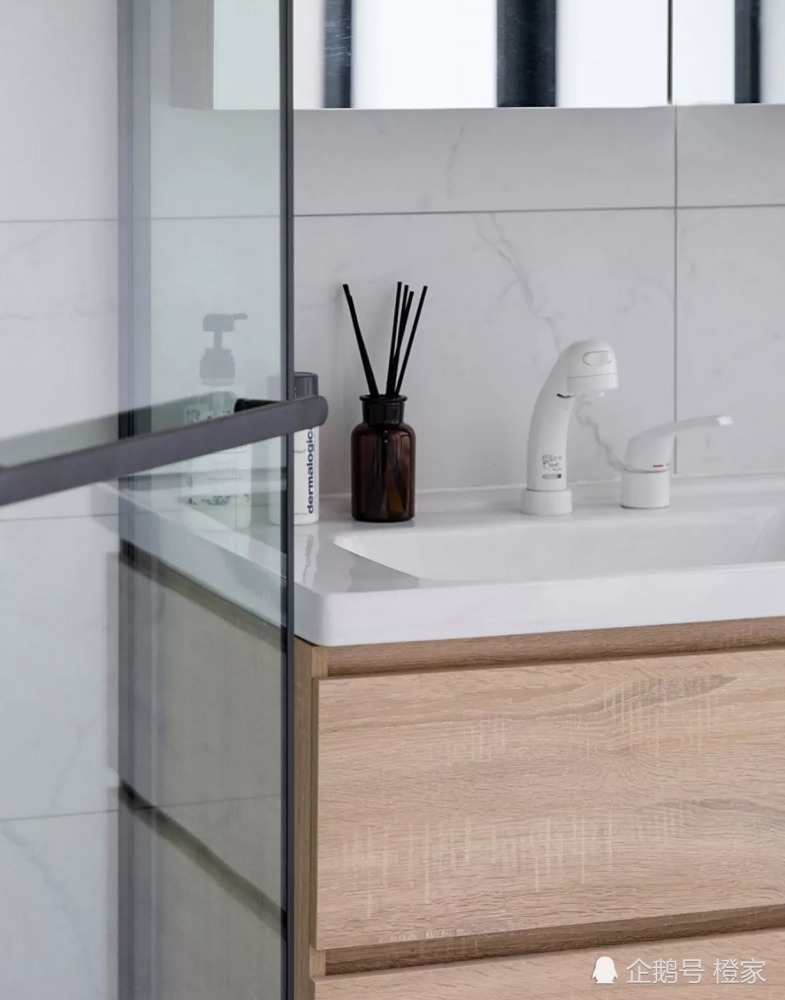 Tủ vanity gắn tường bằng gỗ ấm áp, tạo sự tương phản với bồn rửa màu trắng sạch sẽ. Tủ lưu trữ với cửa gương soi vừa tiết kiệm diện tích vừa 'nhân rộng' căn phòng một cách trực quan.