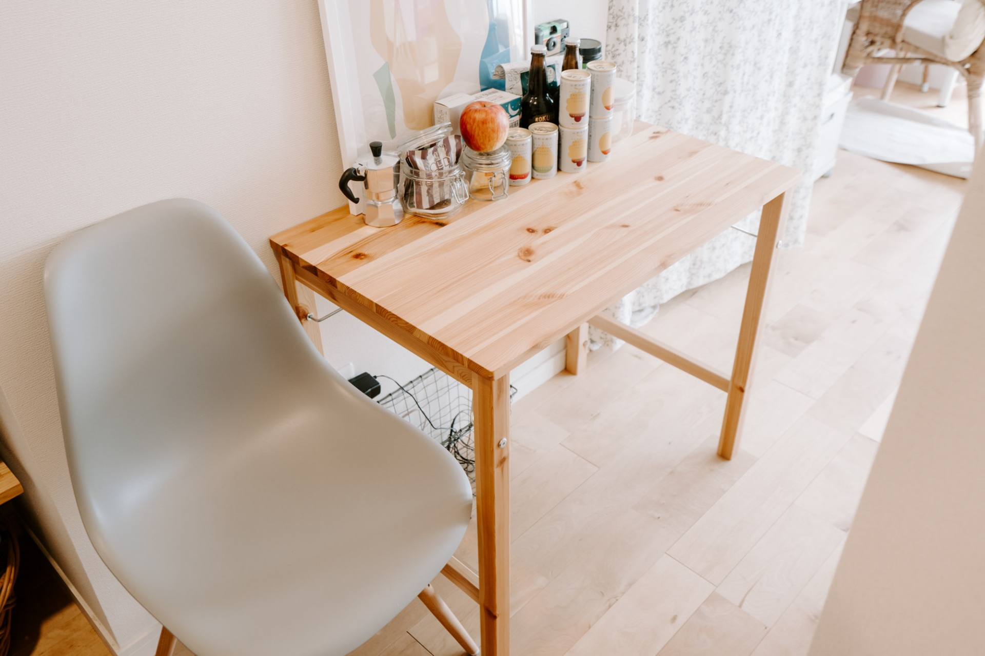 Chiếc bàn gỗ và ghế đơn đặt sát tường, phân cách phòng bếp và phòng làm việc - phòng ngủ. Đây là bàn ăn đồng thời là nơi trưng bày những chai thức uống yêu thích.