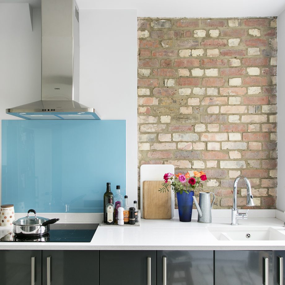 Bức tường ốp gạch thô mộc và backsplash xanh ngọc lam sáng bóng khiến căn bếp hiện đại trở nên gần gũi hơn.