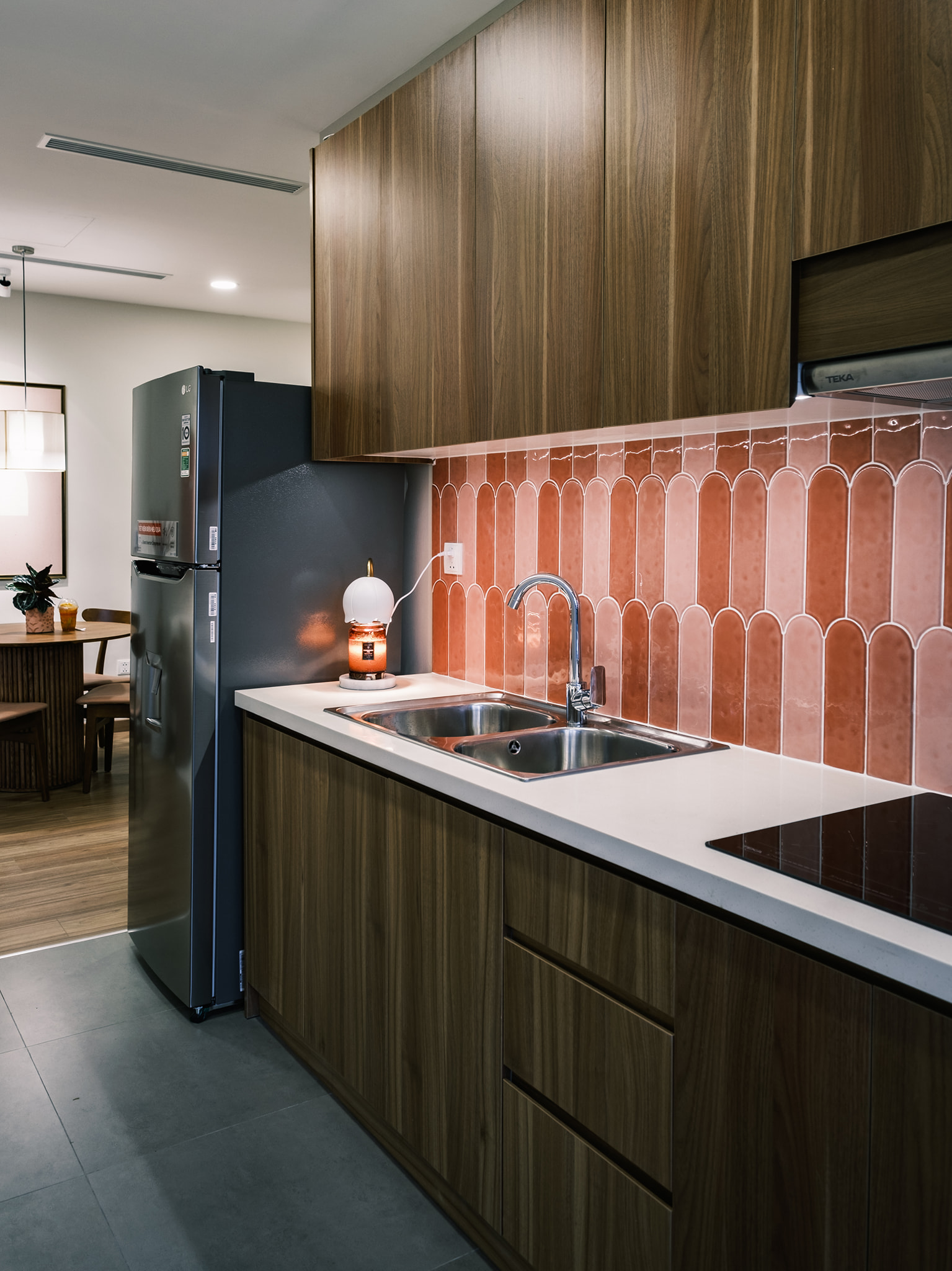 Phòng bếp lát sàn gạch vừa phân vùng với phòng khách - phòng ăn, vừa dễ dàng vệ sinh cho khu vực nấu nướng. Hệ thống tủ lưu trữ gỗ vừa tiện nghi vừa bền đẹp.