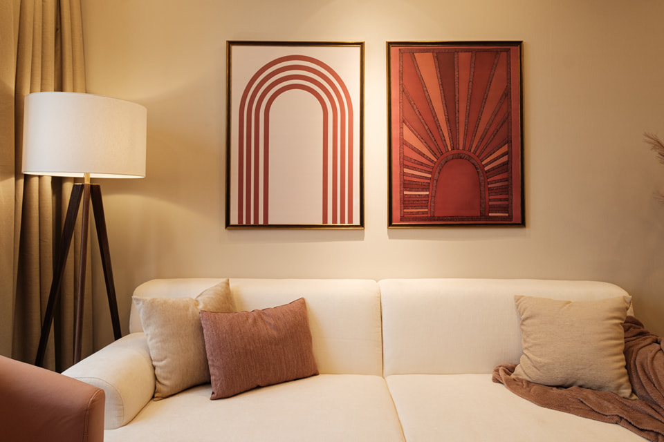 Tranh treo trang trí bức tường sau sofa là sự kết hợp của tone màu hồng dusty pink và đỏ mận để tăng thêm điểm nhấn trên bức tường màu beige.