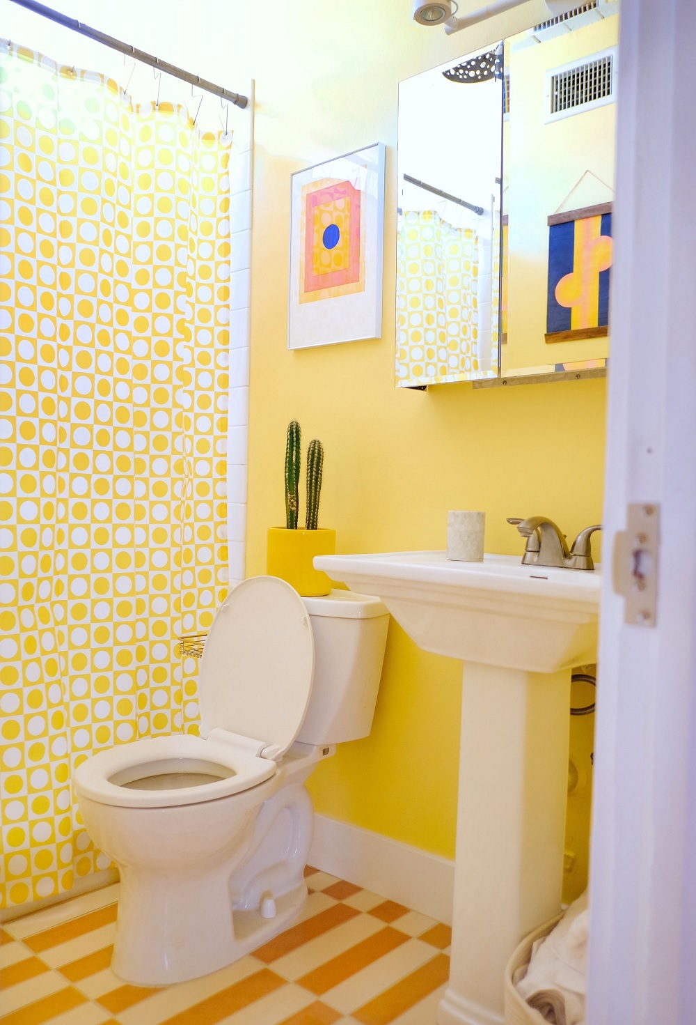 Phòng tắm thiết kế theo phong cách Mid-century với tone màu vàng tươi sáng, kết hợp họa tiết hình học sống động ở cả rèm che và sàn nhà mang đến vẻ bắt mắt ngay từ cái nhìn đầu tiên.