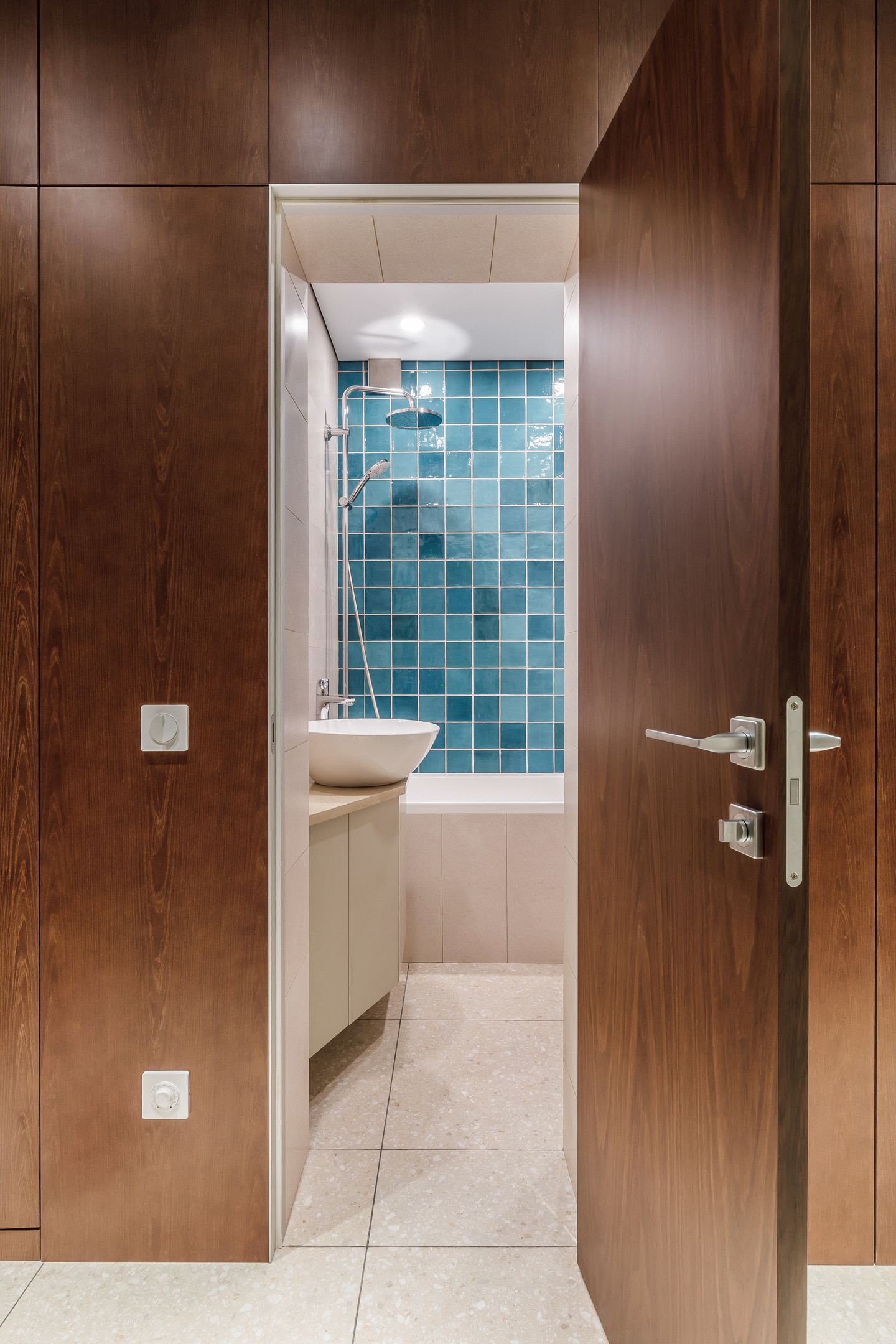 Tường phòng tắm là sự kết hợp giữa sơn màu be và gạch mosaic vuông màu xanh lam hoàn toàn tương đồng với backsplash ở phòng bếp.