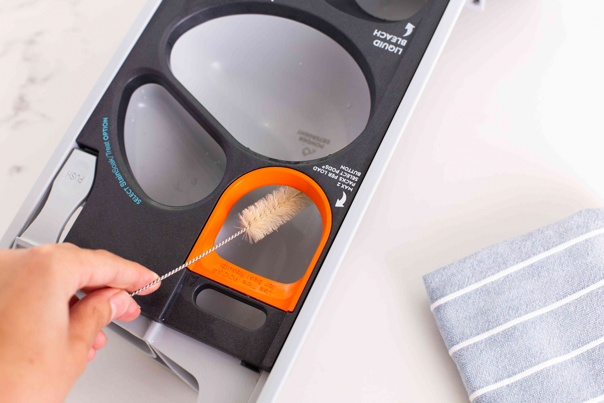 Sử dụng một bàn chải mềm nhỏ để làm sạch phần mở ngăn kéo trên máy giặt. Loại bỏ tất cả cặn bám ở phần trên và phần dưới của hốc.