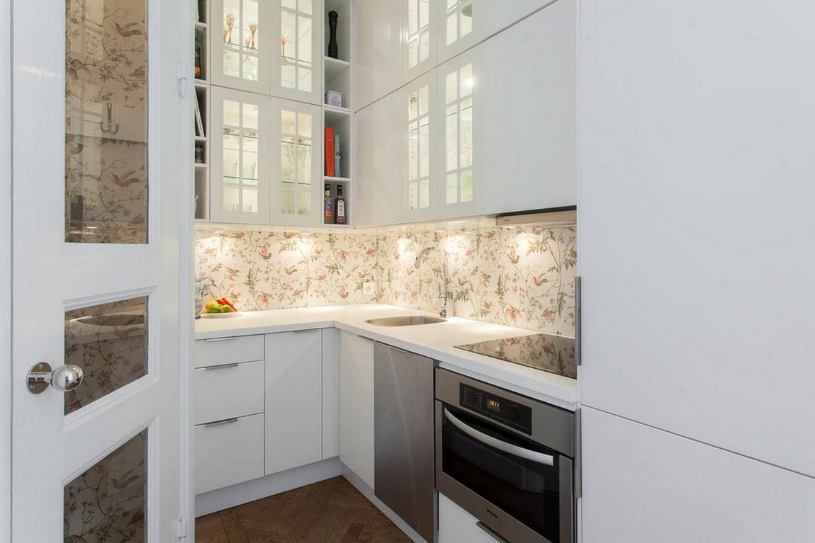 Phòng bếp thiết kế kiểu chữ L phù hợp với cấu trúc của căn hộ, hệ tủ lưu trữ bếp màu trắng sáng với điểm nhấn là giấy dán tường ở khu vực backsplash.