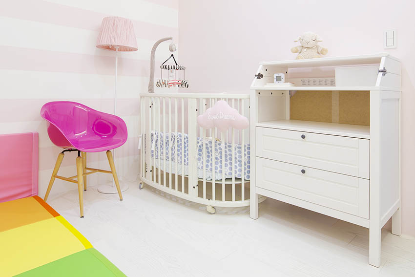 Phòng riêng của bé gái với chiếc cũi nhỏ xinh, tủ lưu trữ gọn gàng và thảm chơi đầy màu sắc. Tone màu chủ đạo là hồng pastel, trắng rất nhẹ nhàng nữ tính.