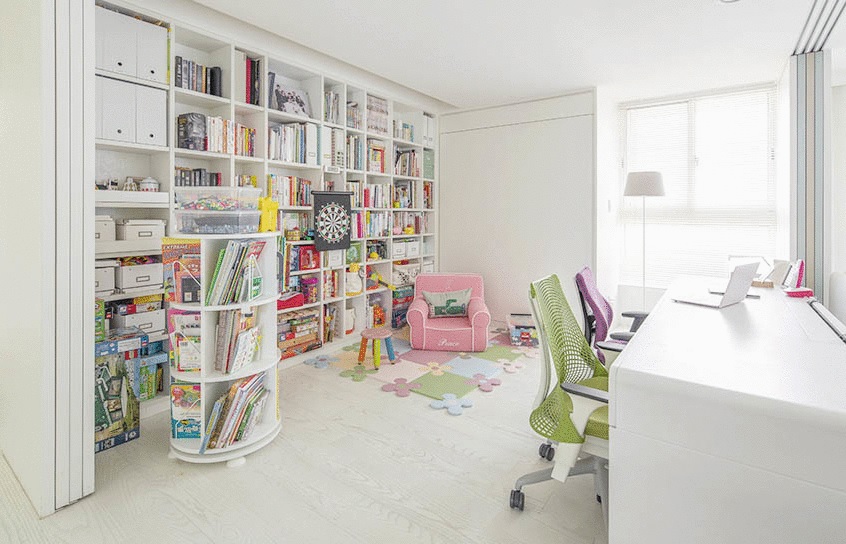 Căn phòng sau sofa thiết kế tích hợp phòng chơi cho trẻ, góc làm việc cho bố mẹ và thư viện chung cho cả gia đình. Chiếc tủ kích thước kịch trần giúp tối ưu hóa không gian lưu trữ.