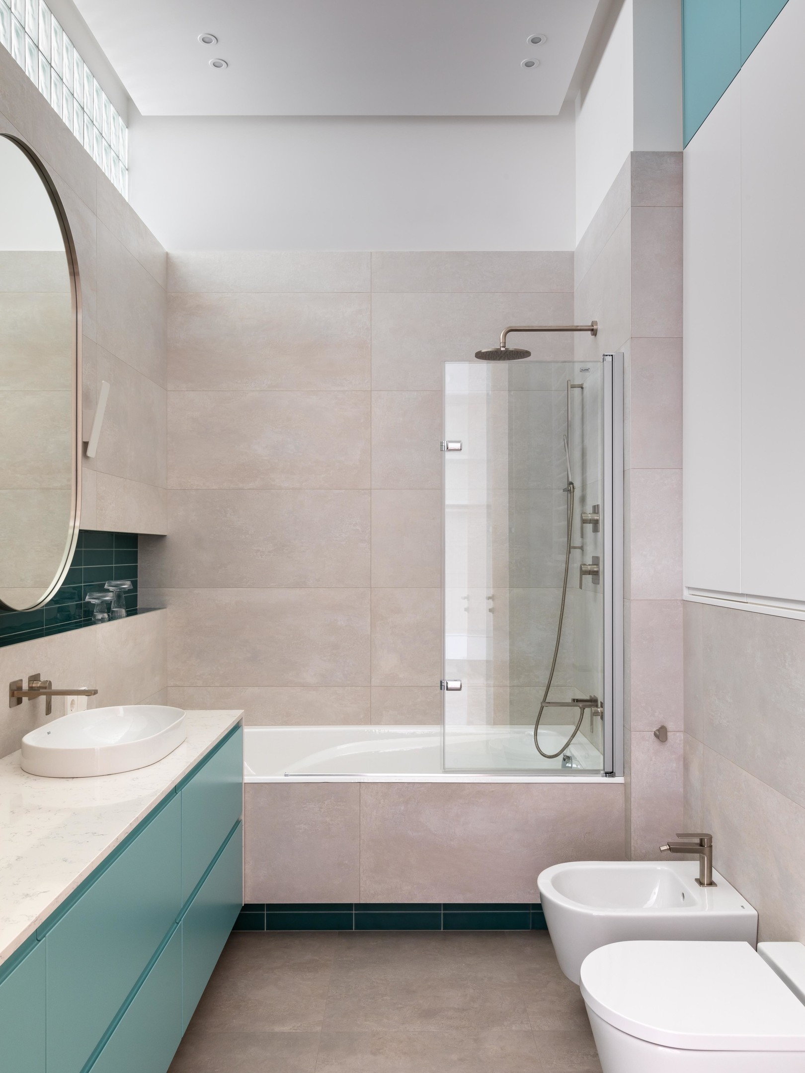Phòng tắm thứ hai ngọt ngào, tươi sáng với các gam màu hồng phấn, xanh lam và xanh ngọc lục bảo nổi bật trên nền trắng. Bồn tắm nằm sử dụng vách ngăn kính trong suốt để phân vùng với nhà vệ sinh.