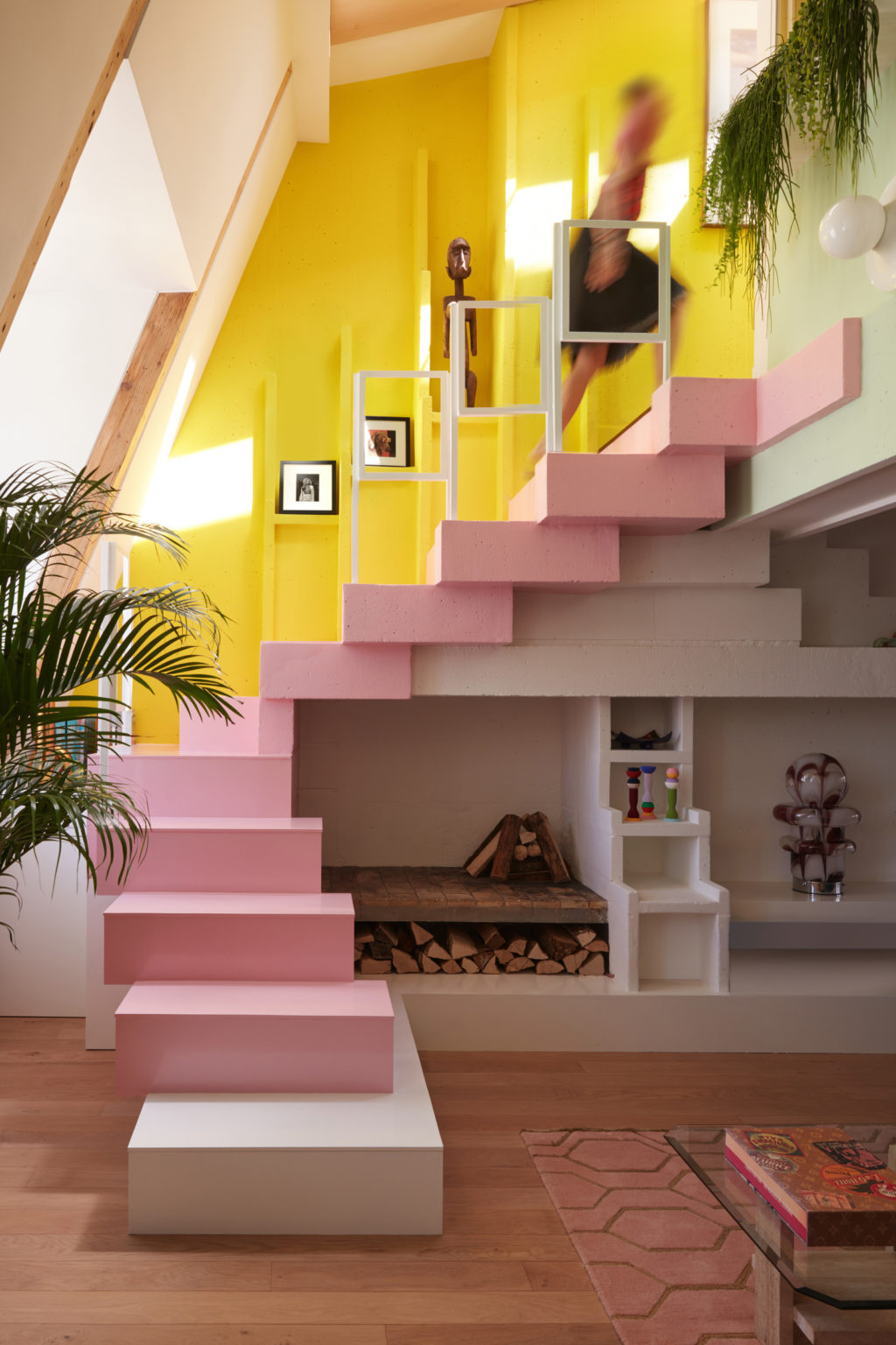Cầu thang dẫn lối lên tầng 2 được sơn màu hồng phấn điệu đà, nữ tính, nổi bật trên sàn gỗ nâu ấm áp và tường trắng thanh lịch. Cây xanh cũng góp phần giúp cho những đường nét cứng nhắc trong nội thất trở nên mềm mại, duyên dáng hơn.