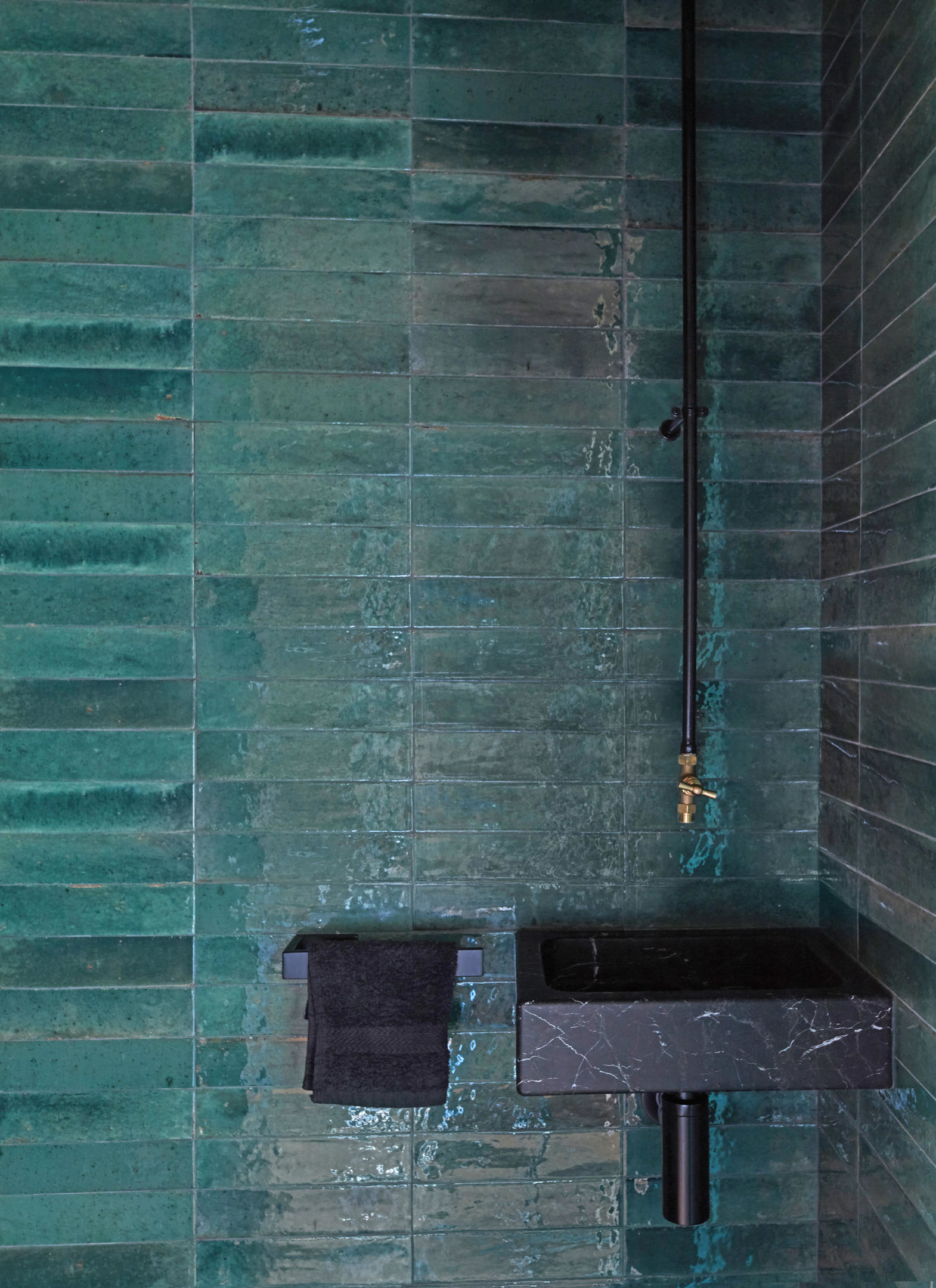 Khu vực bồn rửa tay được NTK lựa chọn ốp gạch màu xanh ngọc lục bảo kết hợp nội thất đen tuyền cho vẻ đẹp vừa thời trang vừa sang chảnh. Kiểu gạch thẻ ngang cũng phần nào giúp 'nới rộng' chiều dài cho không gian nhỏ.