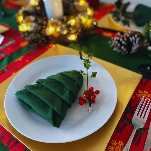 Bạn hãy tạo nên một khung cảnh lễ hội trên bàn tiệc với chiếc khăn ăn màu xanh lá cây đậm xếp thành hình cây thông Noel thu nhỏ cực đỉnh như thế này!