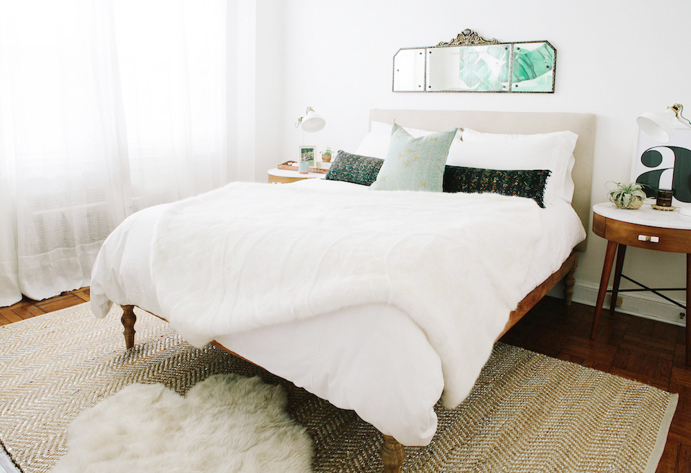 Phòng ngủ sử dụng tone màu trắng từ sơn tường, chăn ga gối cho đến rèm vải mỏng nhẹ. Bức tường đầu giường trang trí tấm gương kiểu dáng cổ điển, phản chiếu bức tranh hình lá chuối ở bức tường đối diện.