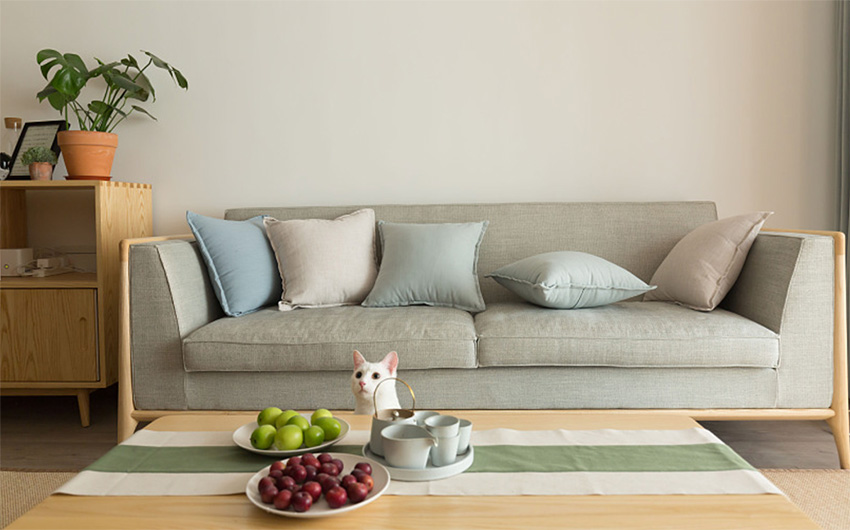 Phòng khách với bộ ghế sofa gam màu xám trung tính kết hợp những chiếc gối với vỏ bọc tone màu pastel dịu nhẹ. Bàn nước bằng gỗ thiết kế thấp sàn có thể được di chuyển ra khu vực logia để tạo thành bàn trà thưởng trà xinh xắn.
