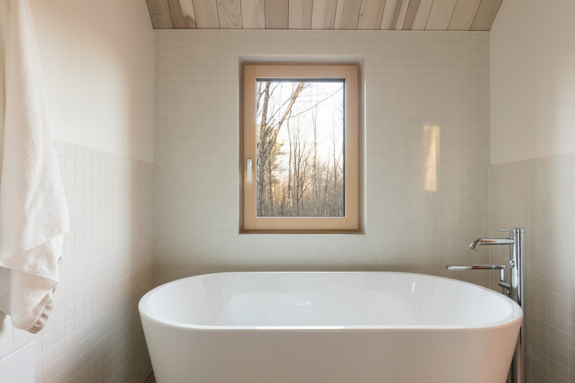 Phòng tắm được lát gạch mosaic vuông màu xám nhẹ nhàng, chiếc bồn tắm nằm bằng sứ bên dưới ô cửa sổ cho chủ nhân cảm giác thư giãn thoải mái. 
