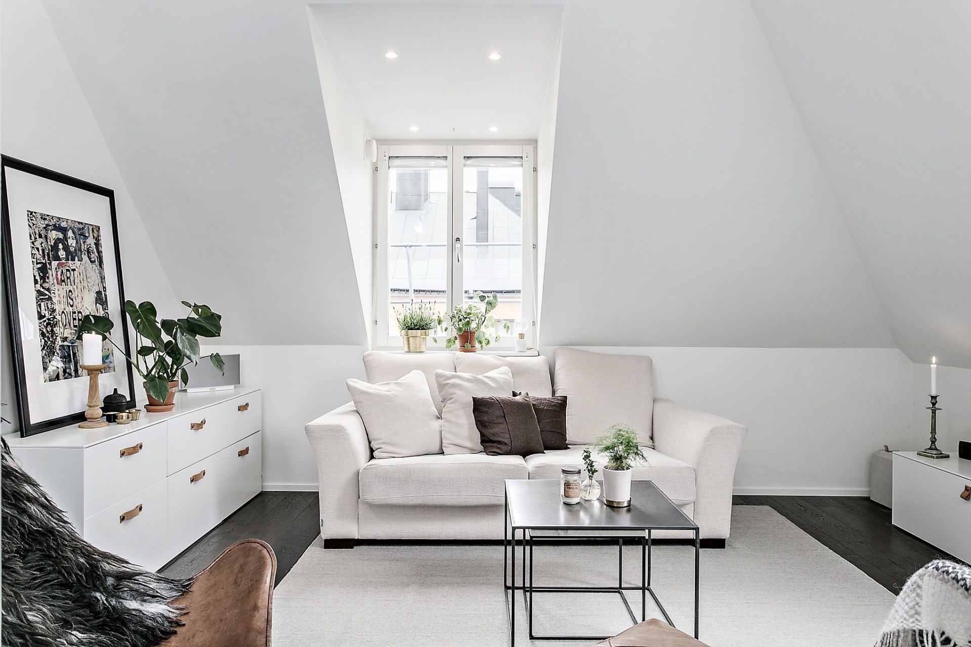 Phòng khách sử dụng ghế sofa, tủ lưu trữ và cả thảm trải sàn đều màu trắng 'tone sur tone' nền tương và tạo sự tương phản nhẹ nhàng với sàn gỗ cùng bàn nước đen bóng.