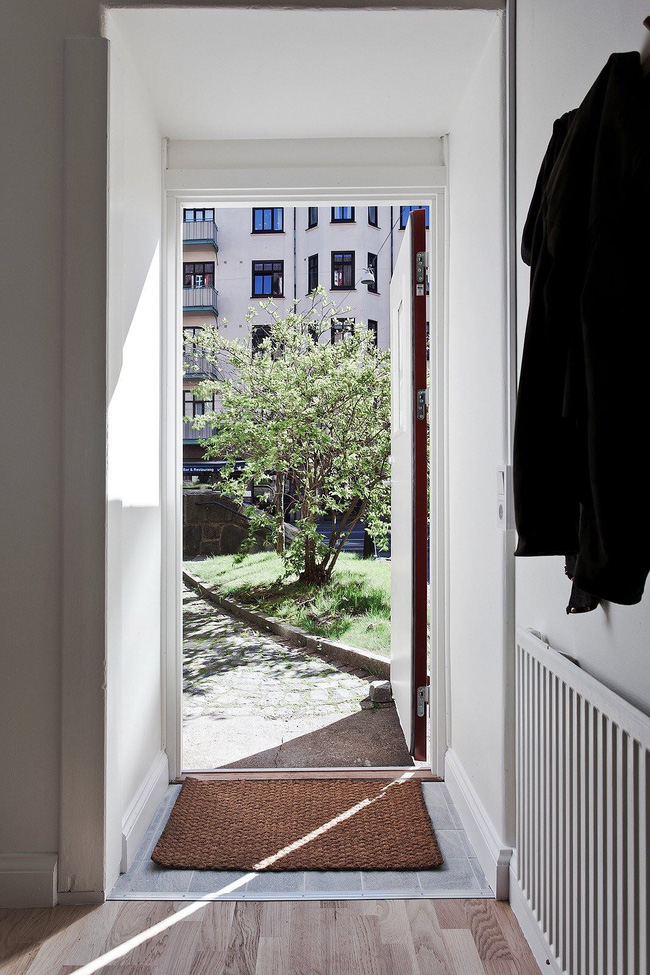 Căn hộ nằm ở tầng trệt của tòa nhà chung cư, từ bên trong nhìn ra ngoài cửa chính là khung cảnh tươi xanh của khuôn viên với cây cối mát mẻ.