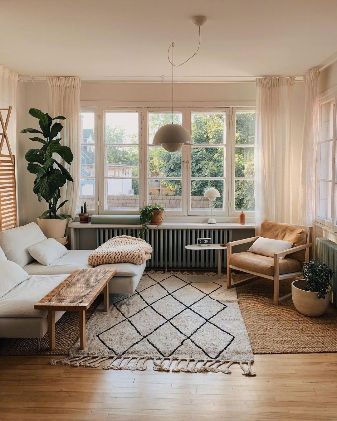 Phòng khách bố trí cạnh ô cửa sổ đầy nắng ấm với 2 chiếc ghế màu trắng êm ái, một chiếc sử dụng như sofa đơn, một chiếc có thể làm giường nghỉ trưa.